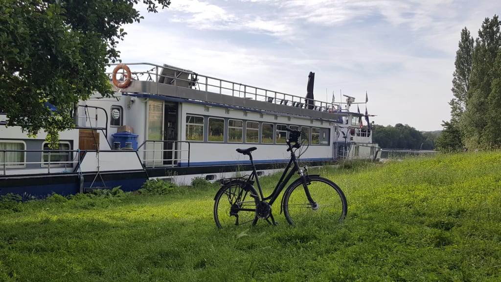 Bici parcheggiata su un prato verde con nave attraccata dietro